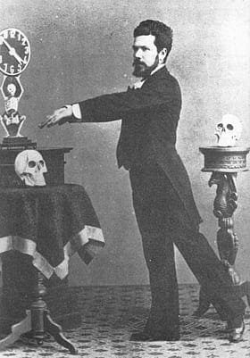 Mago del siglo XIX realizando un truco de magia con calaveras y una figura mecánica.