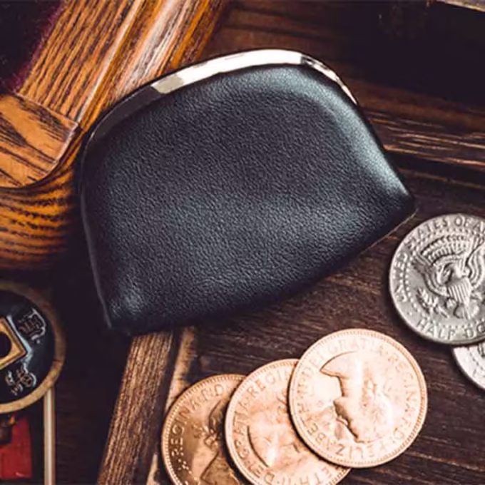 Monedero profesional de cuero negro junto a monedas de magia de Amor Magic.