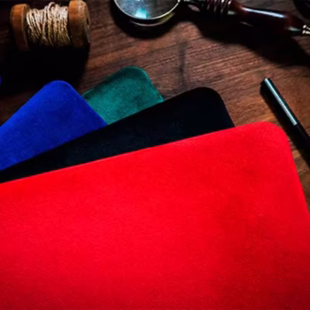Tapete rígido grande de TCC en colores rojo, negro, verde y azul, colocados sobre una mesa de madera junto a accesorios mágicos.