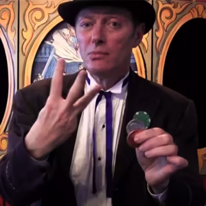 Charlie Frye presentando el efecto 3 Frye Coin con monedas mágicas en un fondo teatral
