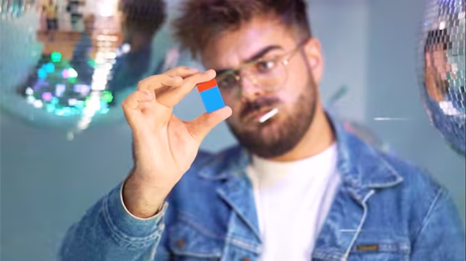 Mago sosteniendo el efecto Ambitious Brick con bloques Lego azul y rojo combinados en primer plano