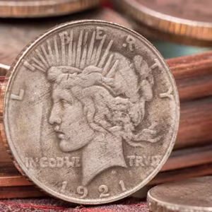 Mini Moneda Dólar de la Paz de 1921 con diseño clásico de la libertad, colocada sobre una superficie de tonos cálidos y rodeada de detalles metálicos.