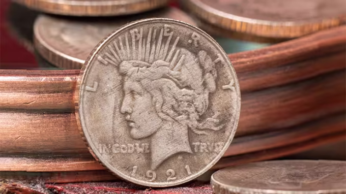 Mini Moneda Dólar de la Paz de 1921 con diseño clásico de la libertad, colocada sobre una superficie de tonos cálidos y rodeada de detalles metálicos.