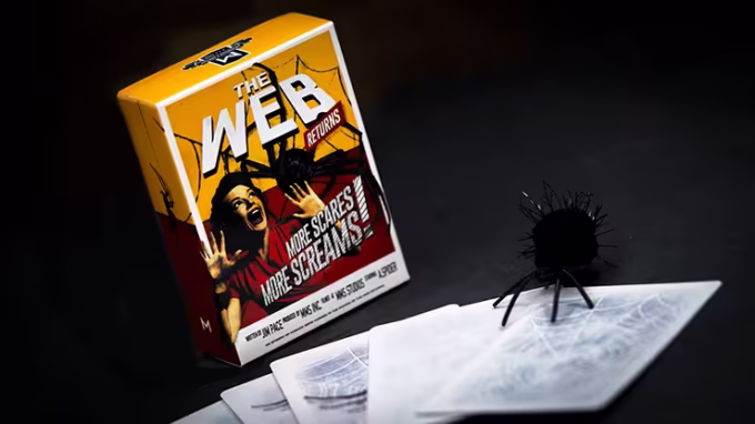 Caja del juego de magia "The Web Returns" de Murphy's Magic acompañada de cartas y una araña de juguete negra, perfecta para rutinas de magia con sustos y efectos impactantes.